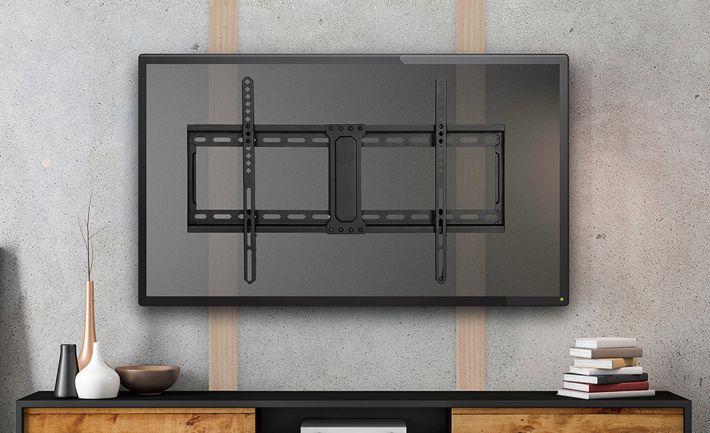 A fixed low-profile mount attached to the back of a TV above a sideboard.