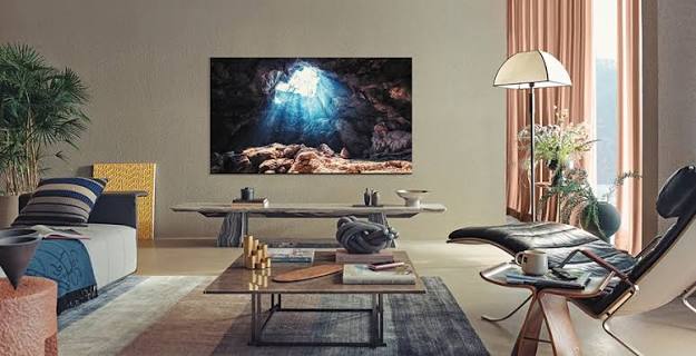 A TV mounted on a textured wall in a bright, furnished living room.