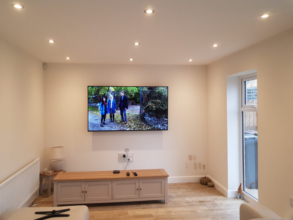 A flat-screen TV mounted neatly on a living-room wall above a low console.